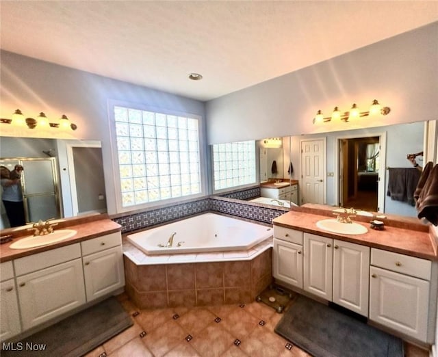 full bath with a tub with jets, two vanities, a sink, and a shower stall