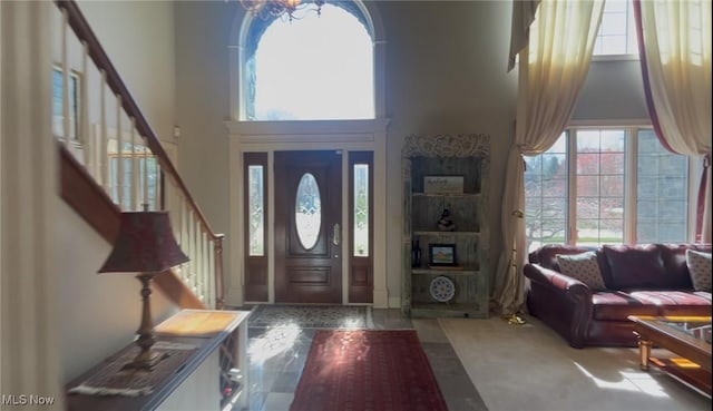 foyer entrance featuring a towering ceiling, a wealth of natural light, and stairs