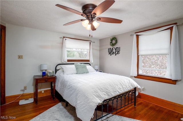 bedroom featuring baseboards, wood finished floors, and ceiling fan