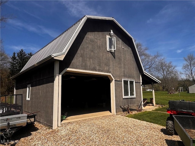 view of property exterior with driveway, an outdoor structure, a barn, metal roof, and a garage