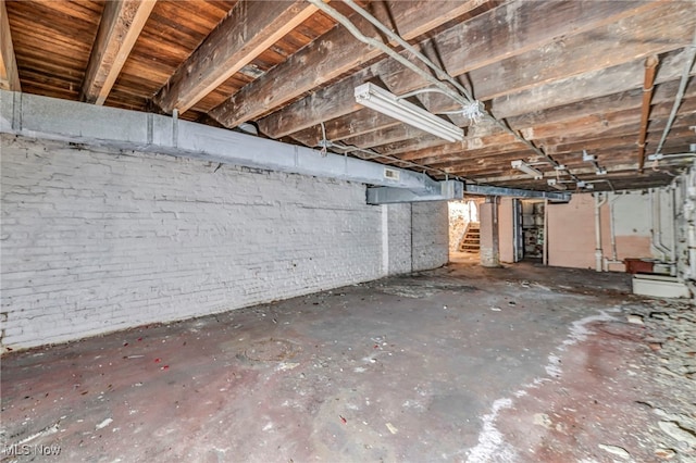 unfinished below grade area featuring stairway and brick wall