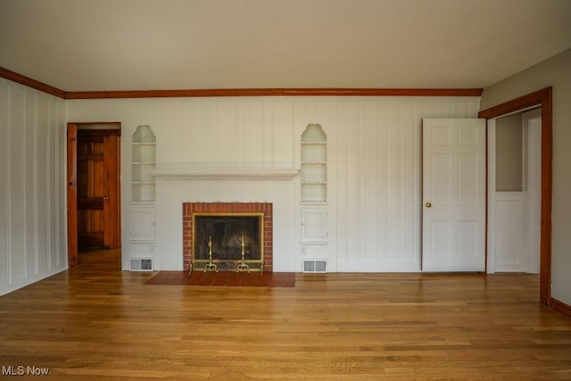 unfurnished living room with visible vents, wood finished floors, and built in features