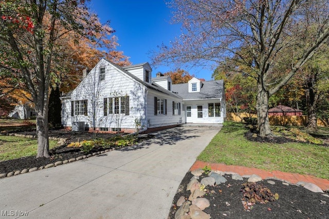 cape cod house with concrete driveway and central AC unit
