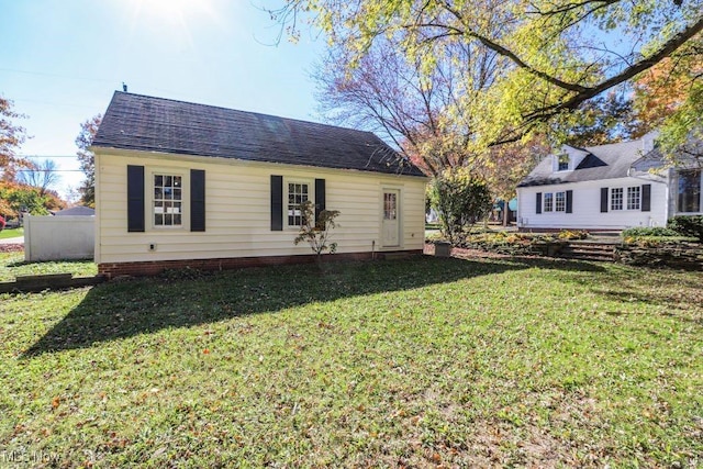 back of property featuring roof with shingles and a yard