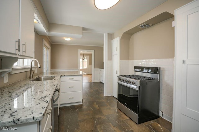 kitchen featuring white cabinetry, a sink, visible vents, stainless steel appliances, and wainscoting