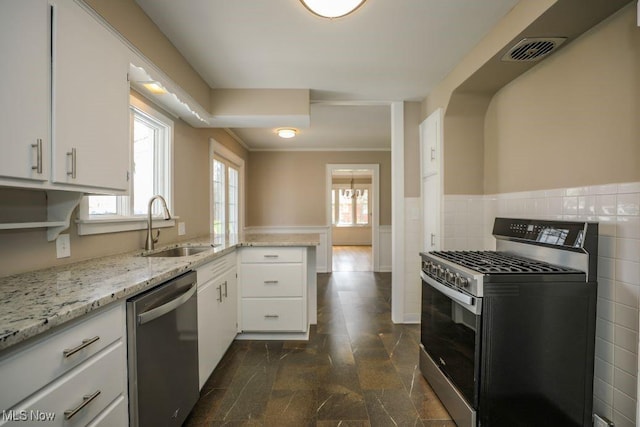 kitchen featuring a sink, stainless steel appliances, visible vents, white cabinetry, and wainscoting