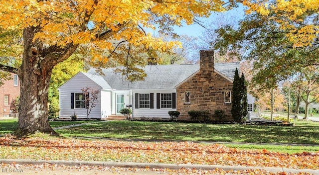 back of house with a chimney, a yard, and a shingled roof