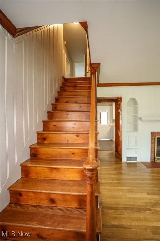 stairs with a fireplace, wood finished floors, and visible vents