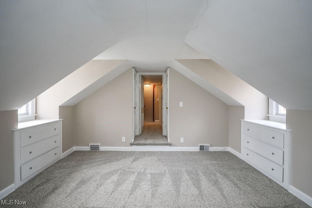 additional living space featuring baseboards, visible vents, carpet floors, and lofted ceiling
