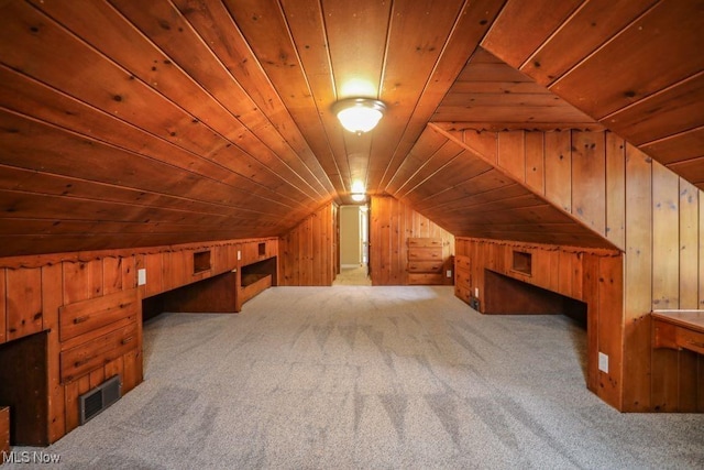 additional living space featuring wooden walls, carpet, and lofted ceiling