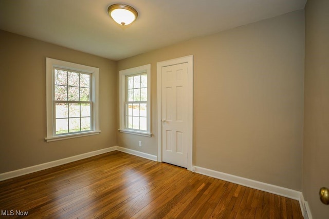 spare room featuring baseboards and dark wood-style floors