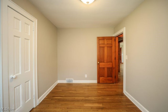 unfurnished room with baseboards, visible vents, and wood finished floors