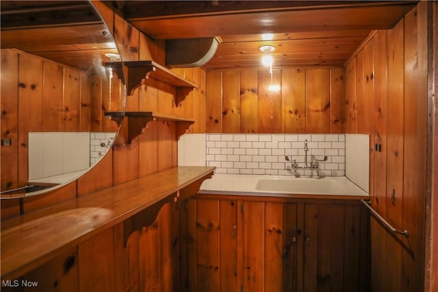 interior space featuring wood walls, wooden ceiling, and a sink