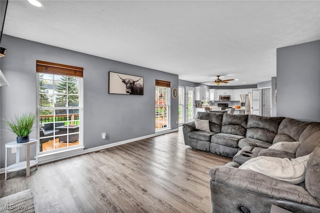 living area with wood finished floors, ceiling fan, recessed lighting, and baseboards