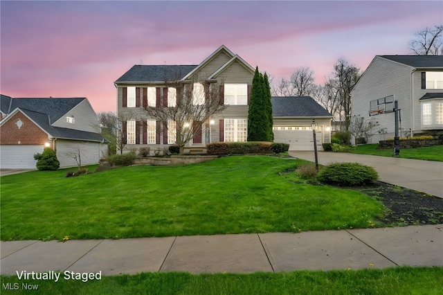 colonial house featuring a lawn, concrete driveway, and a garage