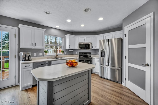 kitchen with recessed lighting, appliances with stainless steel finishes, light countertops, white cabinets, and a sink