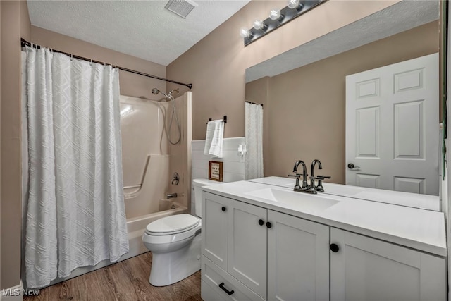 full bath featuring vanity, toilet, visible vents, a textured ceiling, and wood finished floors