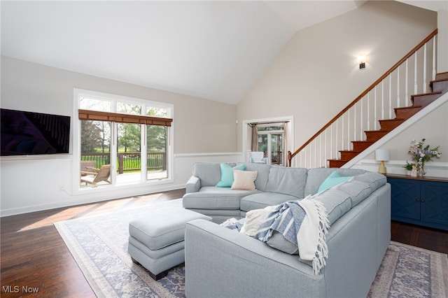 living room featuring dark wood-style flooring, high vaulted ceiling, and stairs