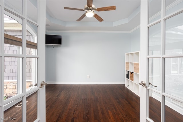 unfurnished living room with baseboards, a raised ceiling, and dark wood-style floors