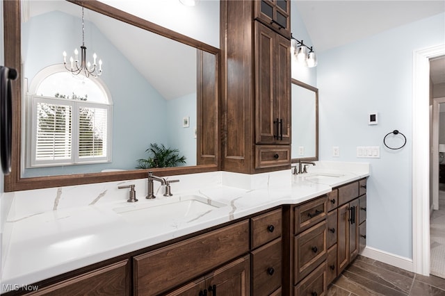 full bathroom with a chandelier, double vanity, lofted ceiling, and a sink