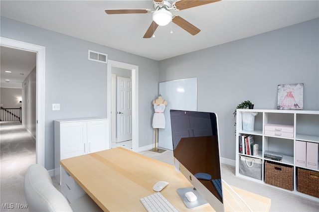 home office featuring baseboards, visible vents, a ceiling fan, and light carpet