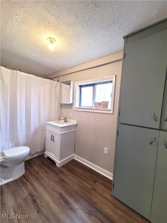 1024 Cleveland St SW, Massillon, OH 44647 - full bathroom featuring wood finished floors, a textured ceiling, toilet, and vanity