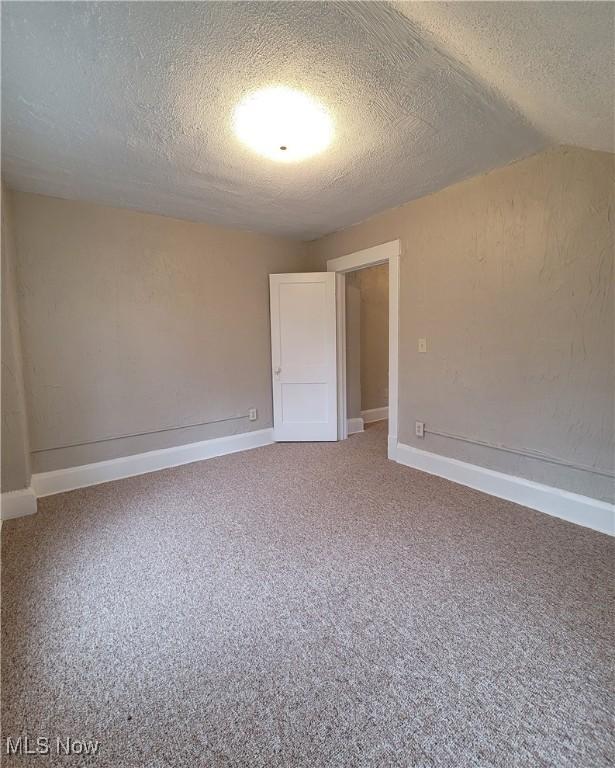 1024 Cleveland St SW, Massillon, OH 44647 - carpeted spare room with a textured ceiling, vaulted ceiling, and baseboards