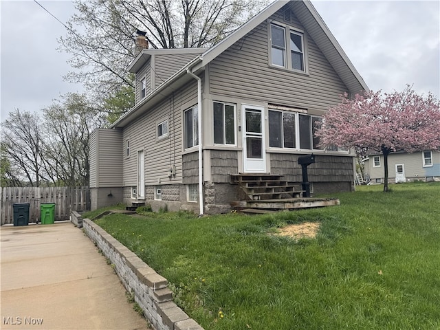 view of front facade with fence, a chimney, entry steps, and a front lawn