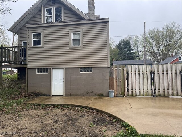 rear view of house featuring fence, a deck, and a chimney