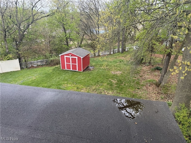 view of yard featuring an outdoor structure, a storage shed, and fence