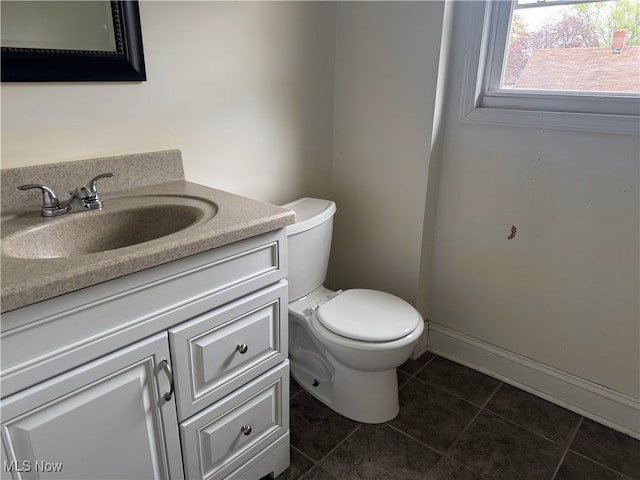 half bathroom with baseboards, toilet, tile patterned flooring, and vanity
