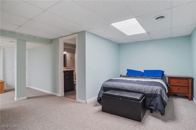 carpeted bedroom with visible vents, connected bathroom, a paneled ceiling, and baseboards