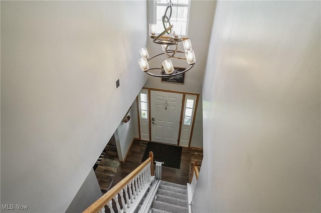entrance foyer featuring a towering ceiling, an inviting chandelier, stairway, and wood finished floors