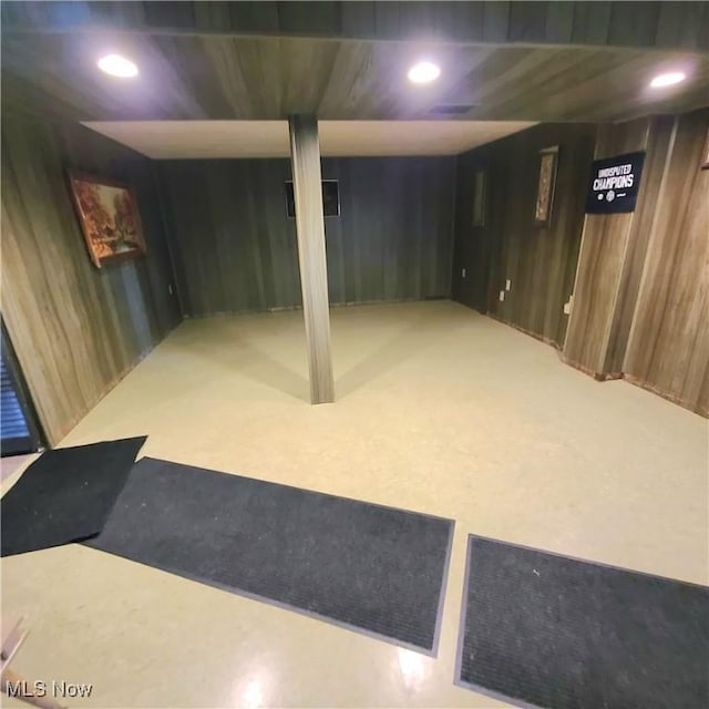 finished basement featuring recessed lighting, wooden walls, and carpet