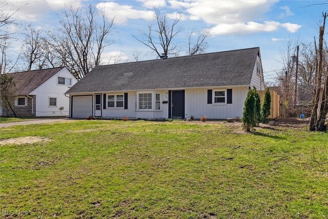 view of front of home featuring aphalt driveway, roof with shingles, fence, a front lawn, and a garage