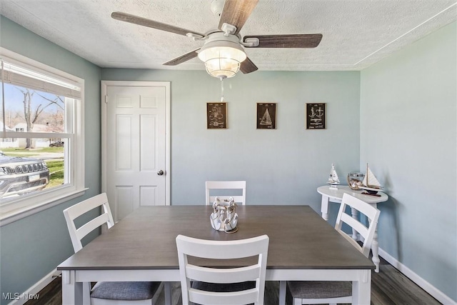 dining area featuring a textured ceiling, ceiling fan, baseboards, and dark wood-type flooring