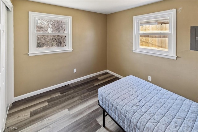 bedroom featuring electric panel, wood finished floors, and baseboards