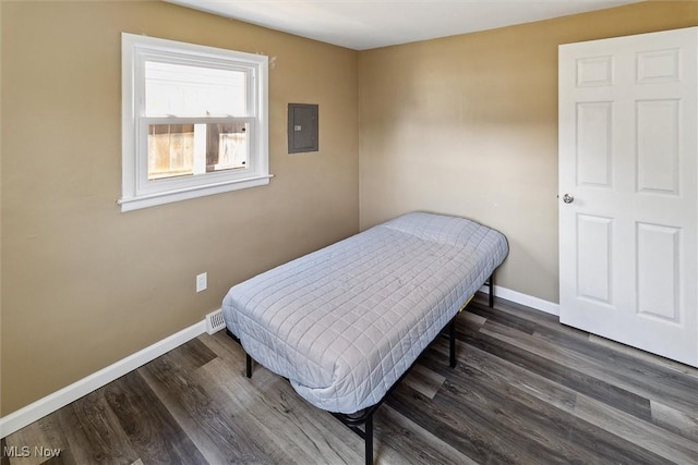 bedroom with baseboards, wood finished floors, and electric panel