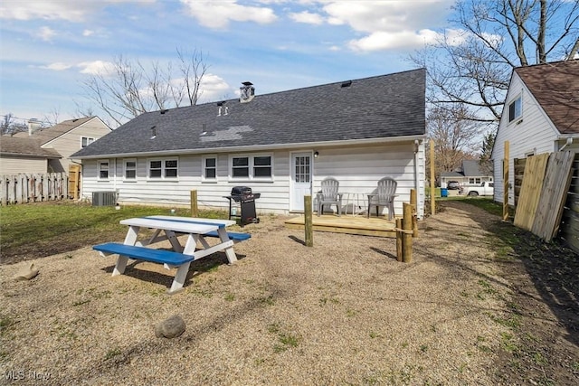 rear view of house featuring a deck, a chimney, roof with shingles, fence, and central AC unit