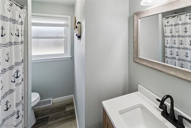 bathroom with visible vents, baseboards, toilet, wood finished floors, and vanity