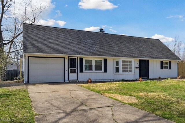 view of front facade featuring driveway, roof with shingles, a front lawn, and a garage