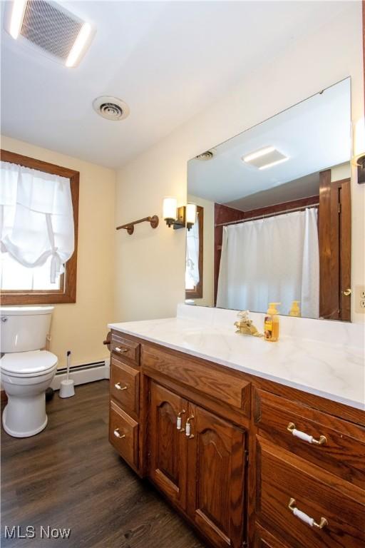 bathroom with baseboard heating, visible vents, wood finished floors, and toilet
