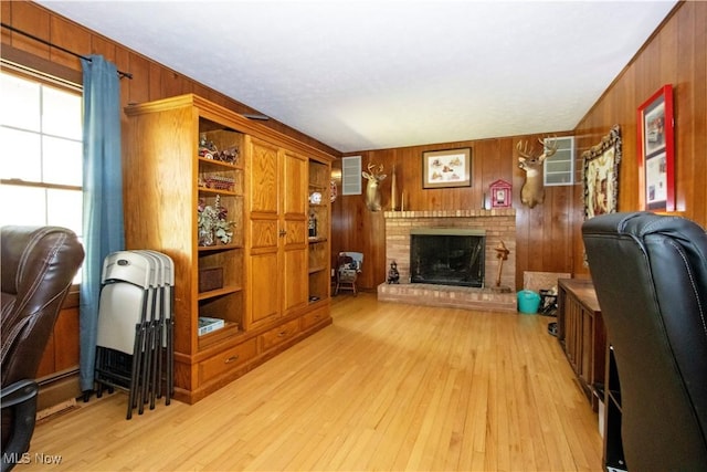 home office featuring wood walls, a fireplace, and light wood finished floors