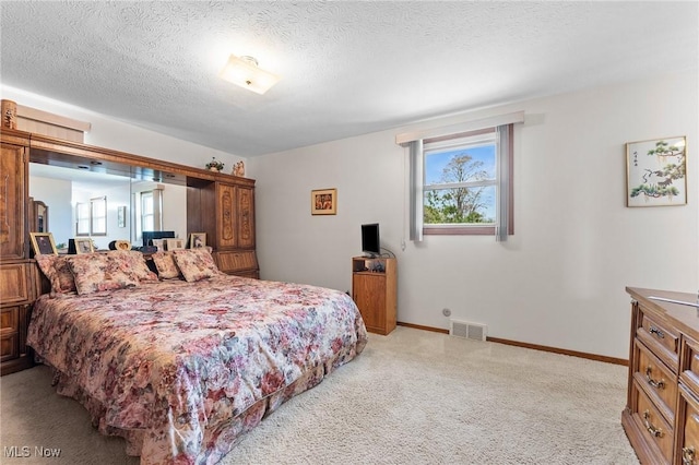 bedroom featuring visible vents, a textured ceiling, baseboards, and light carpet