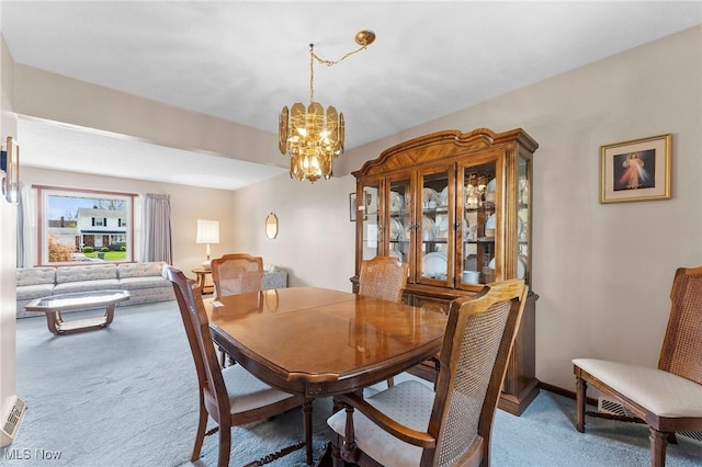 carpeted dining room with baseboards and a chandelier