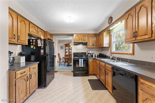 kitchen with brown cabinets, dark countertops, a sink, and black appliances