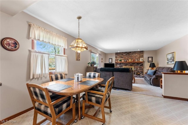 dining space featuring a brick fireplace, baseboards, an inviting chandelier, and light floors