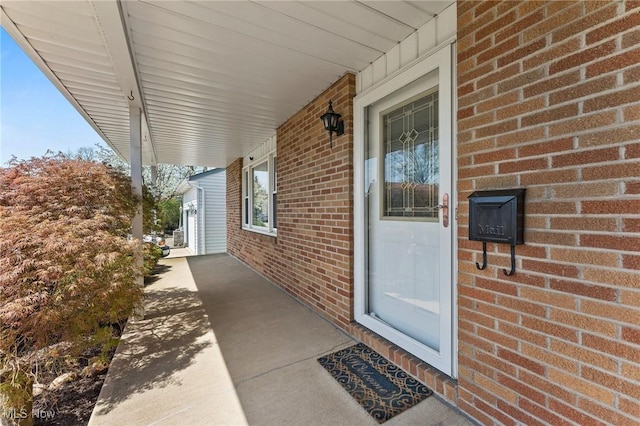 entrance to property featuring a porch and brick siding