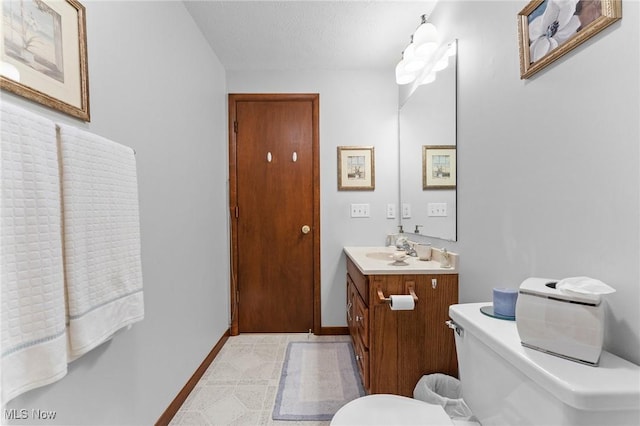 half bathroom with baseboards, toilet, and vanity
