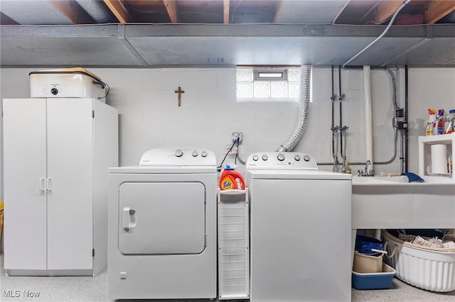 clothes washing area with laundry area, concrete block wall, and washing machine and clothes dryer